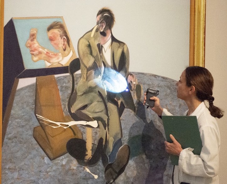 Restauradora examinando la superficie pictórica de la obra, en las salas de la colección