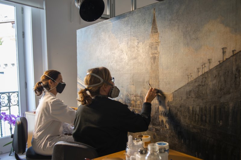 Restorers in the process of cleaning Canaletto's “The Piazza San Marco in Venice”
